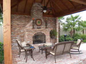 Outdoor living area with brown and white patio furniture and a fireplace.