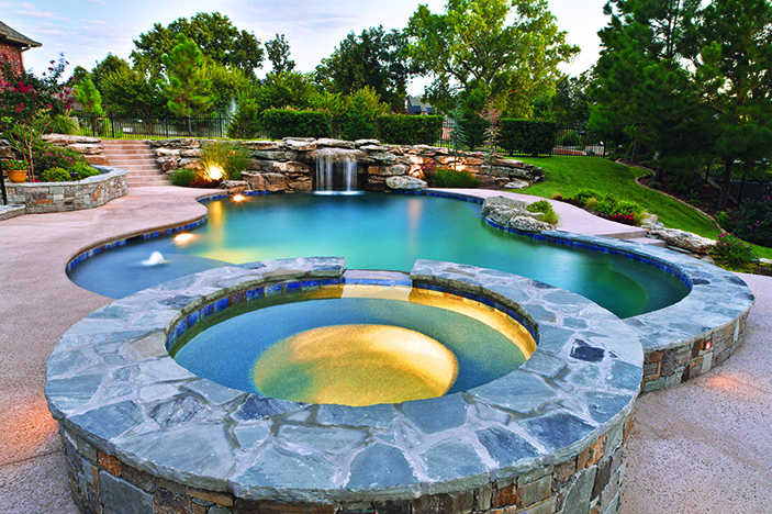 A beautiful pool design by Ewing Aquatech that is enhanced by ambient pool lighting.